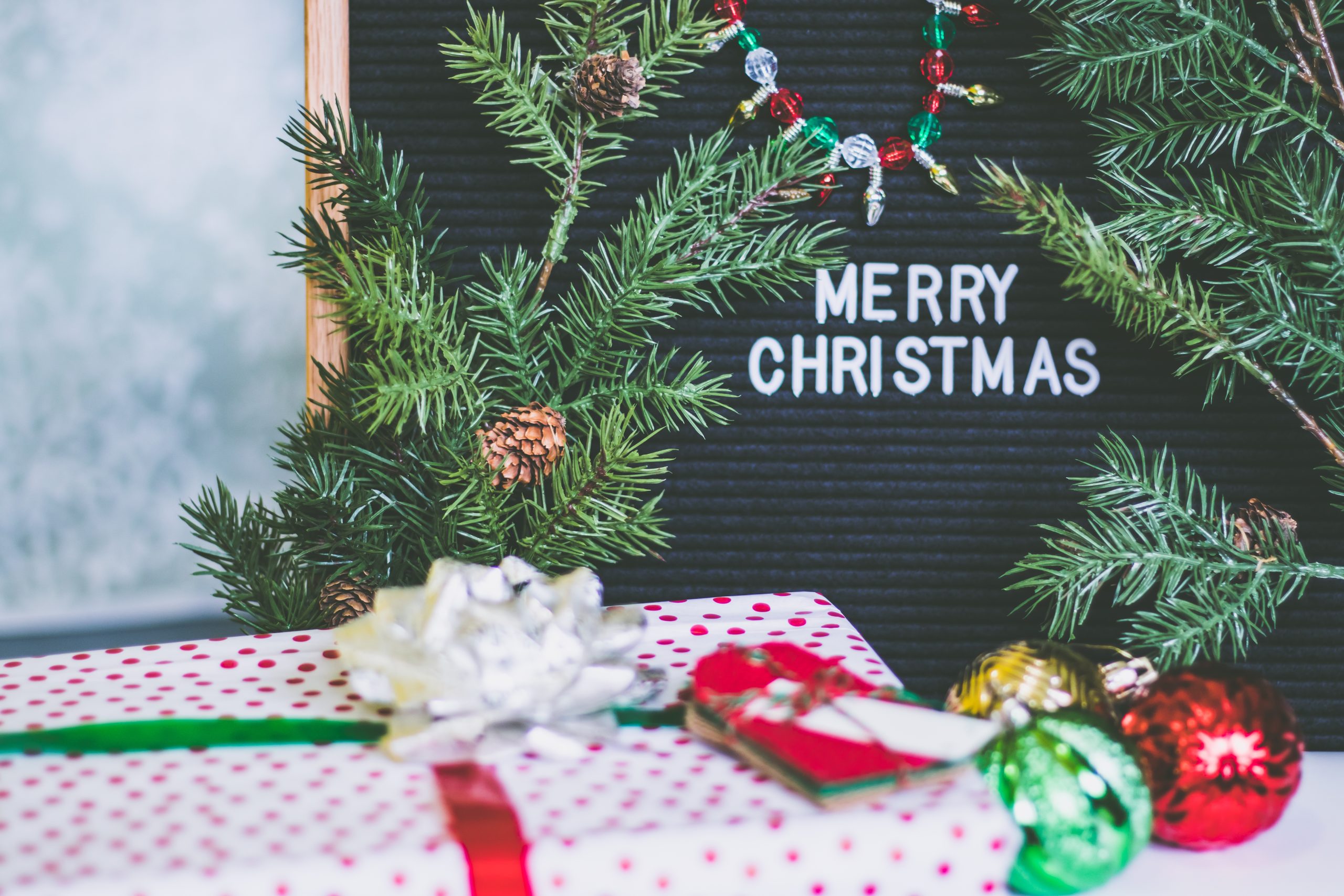 "Merry Christmas" written on a board surrounded by tree branches, presents, and ornaments. This highlights the importance for a sober Christmas for those in recovery.