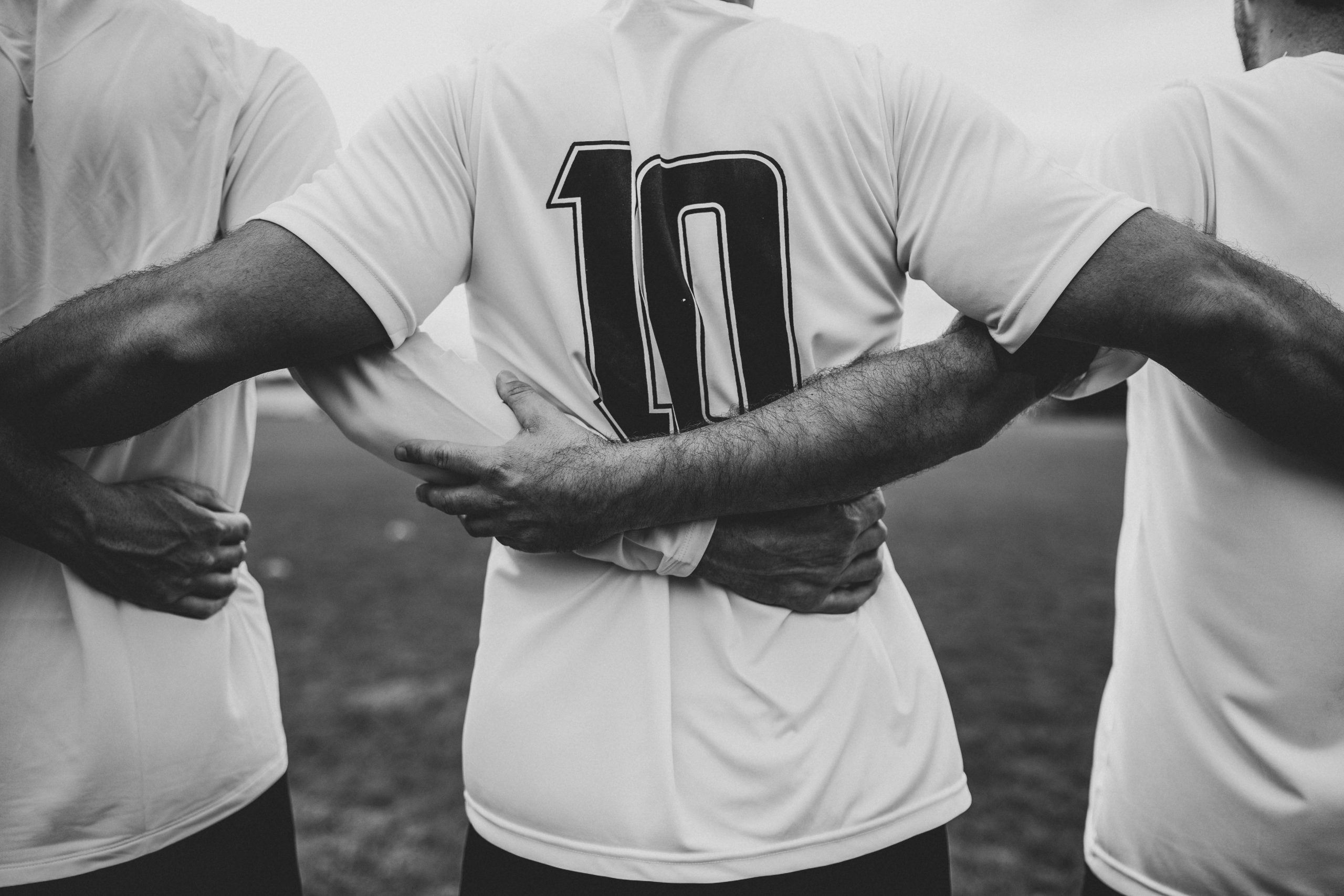 Soccer player with number 10 on his back, locking arms with teammates to show the 10 benefits of residential treatment