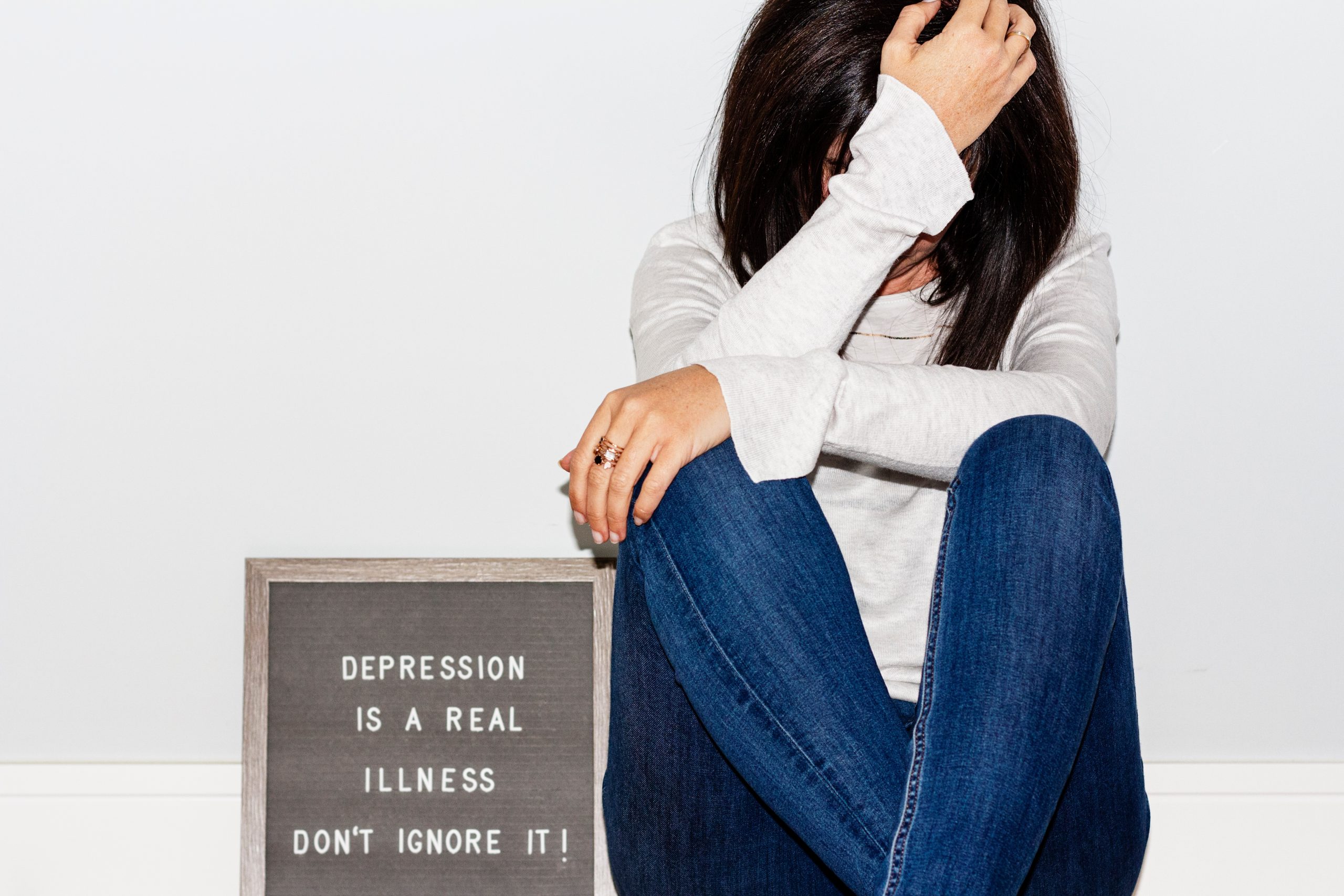 a woman with a and on her head next to a sign that reads "depression is a real illness don't ignore it!" highlighting dysthmia vs depression