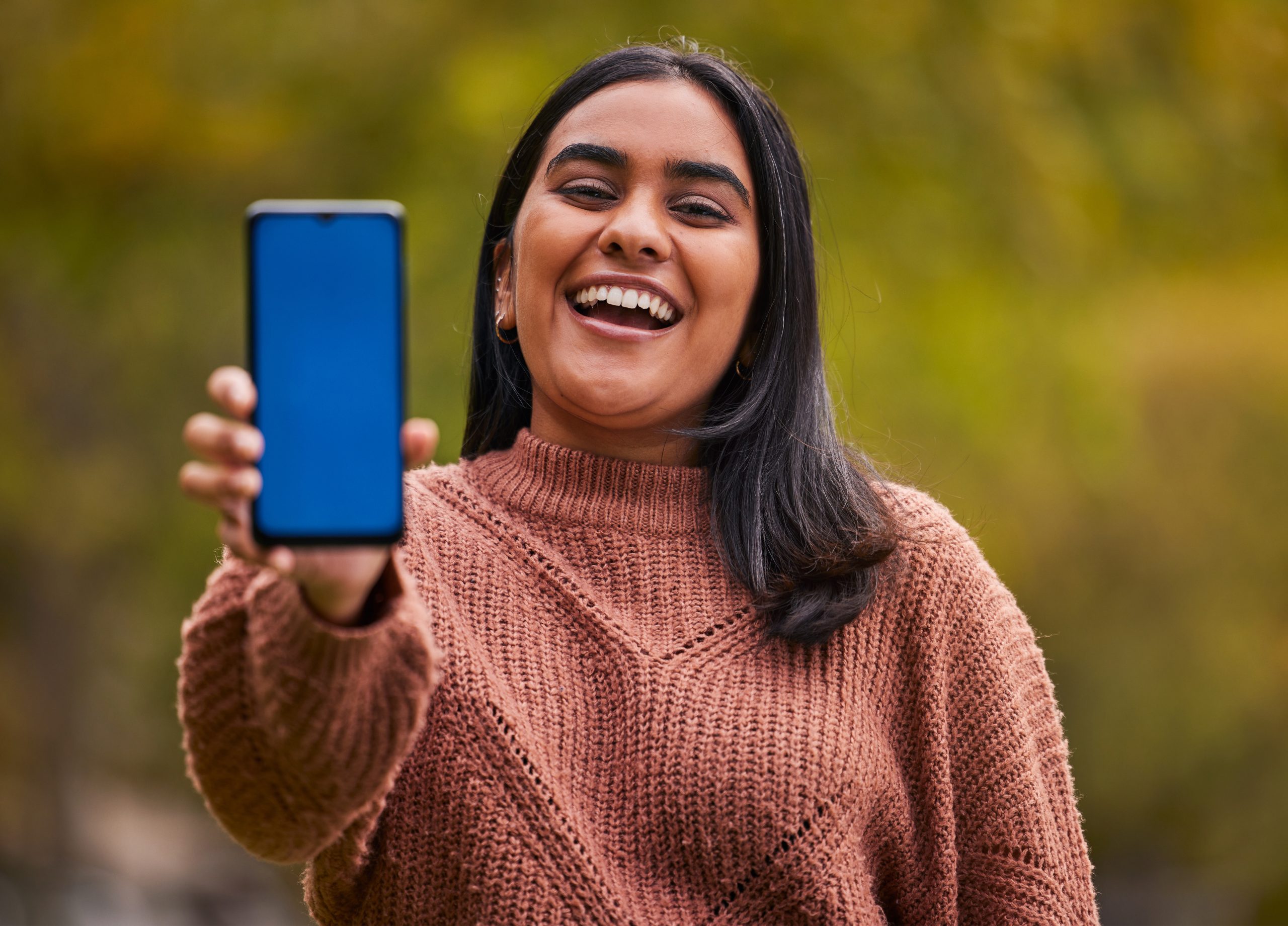 a smiling woman holding up a phone with the Trac9 app