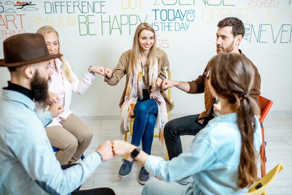 people sitting in a circle with their hands together during substance abuse group therapy
