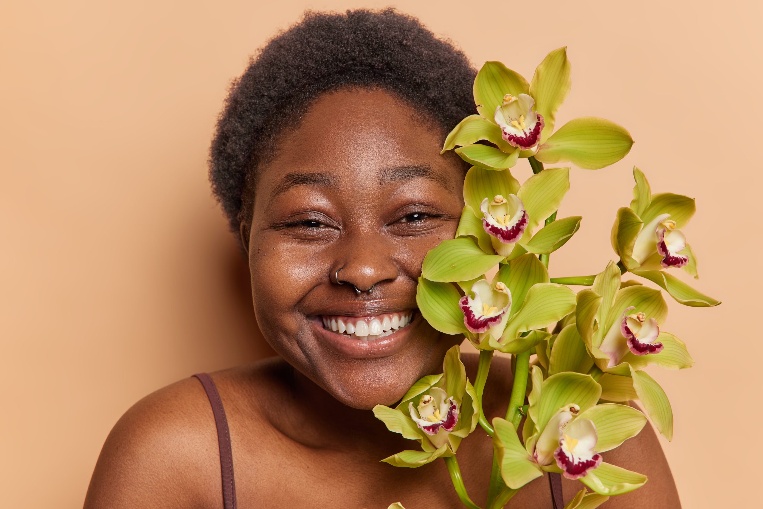 a cheerful black woman holding flowers and smiling at us, symbolizing the importance of caring for yourself on National Self Care Day