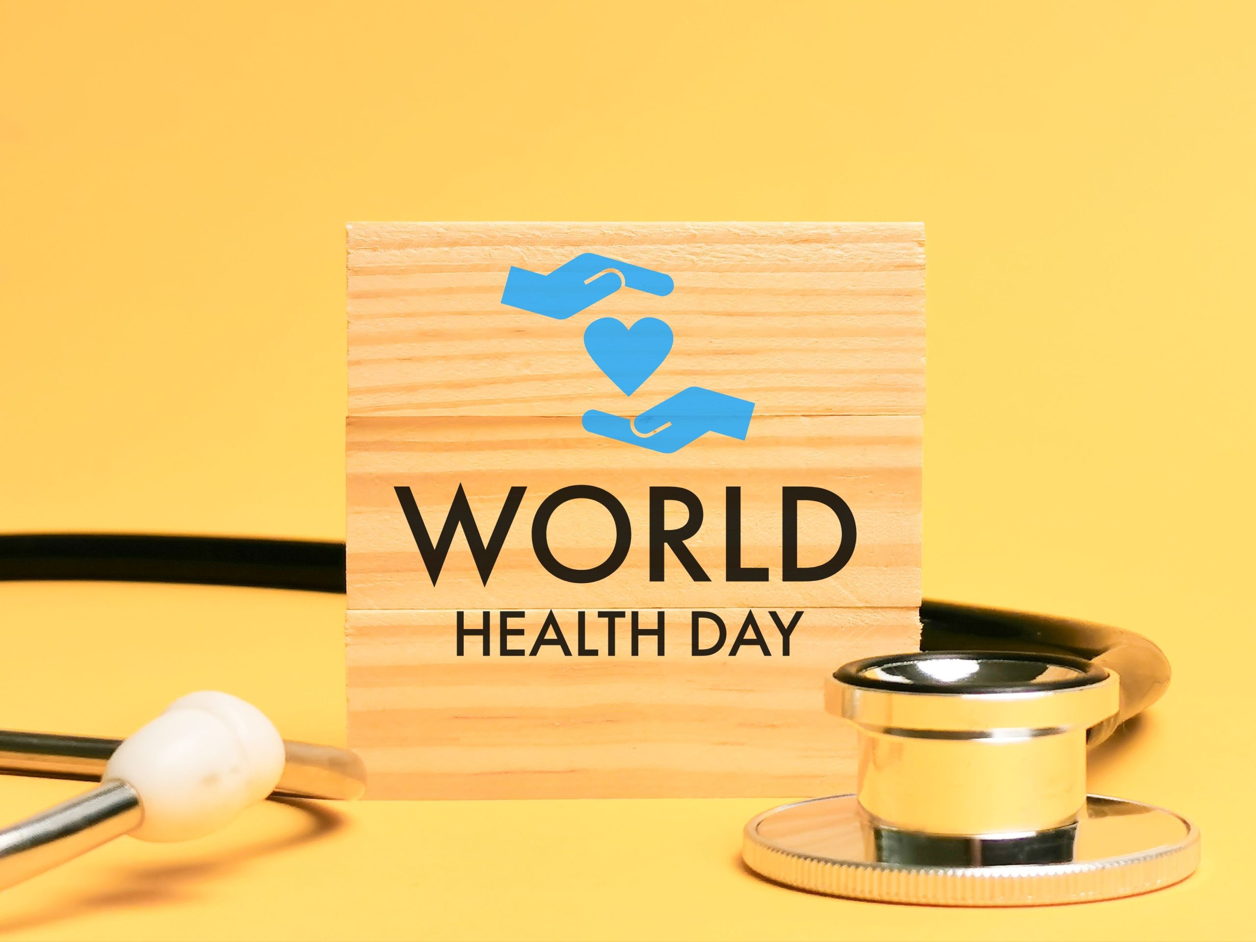 A wooden sign with the words 'World Health Day' written upon it, set against a background of a stethoscope