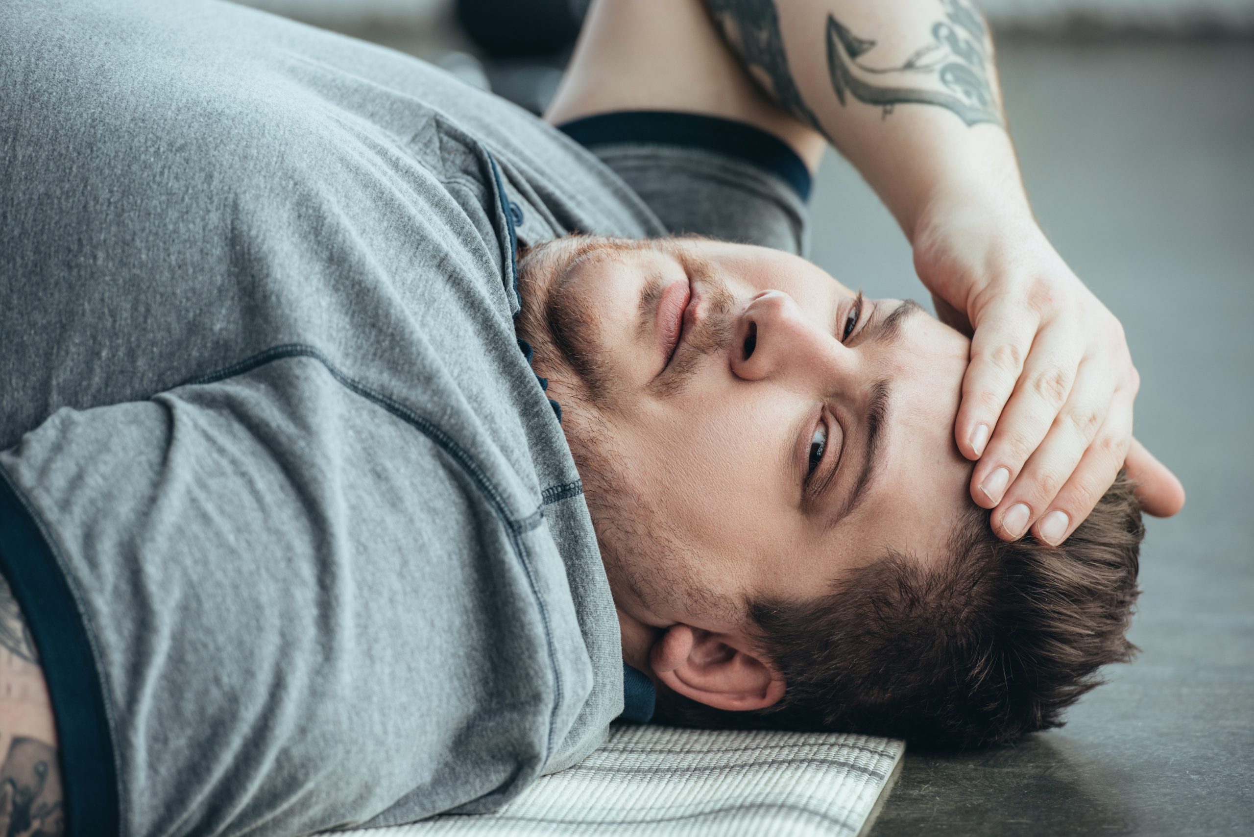 an exhausted tatooed man looking at us, as he is battling sobriety fatigue