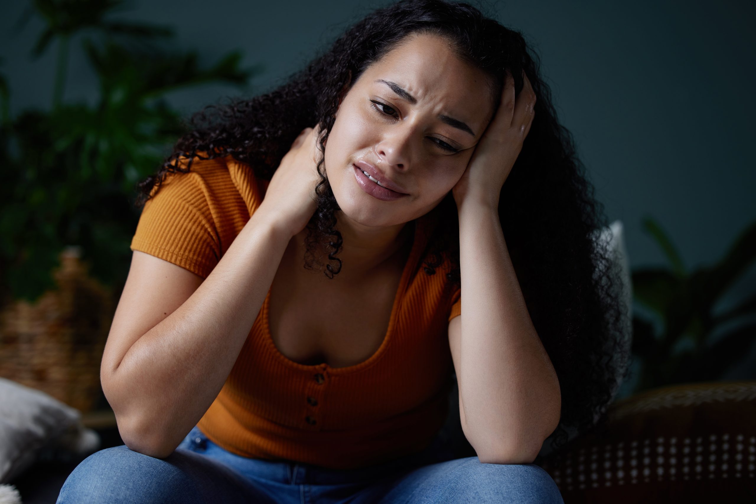 a woman sitting on her couch at home, feeling extreme hanxiety