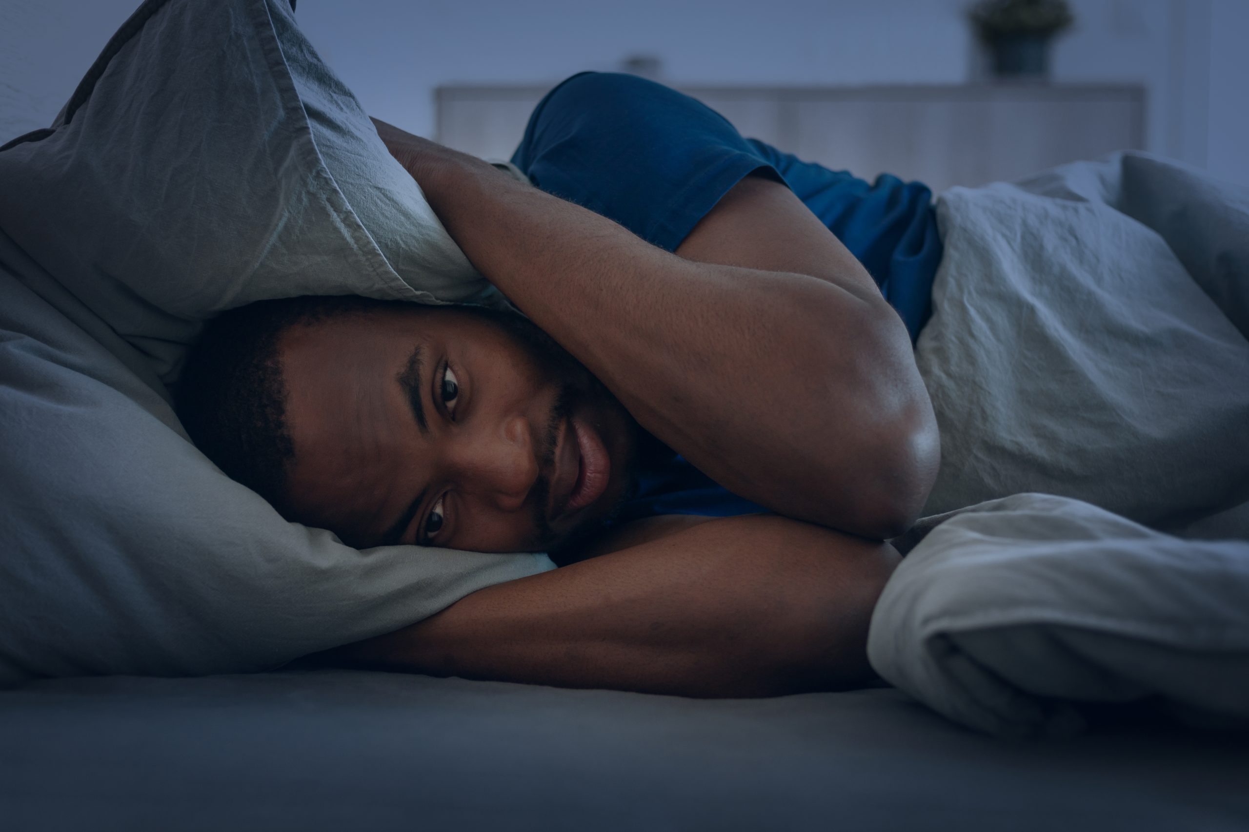 a man cover ears with a pillow, suffering from Ambien and alcohol