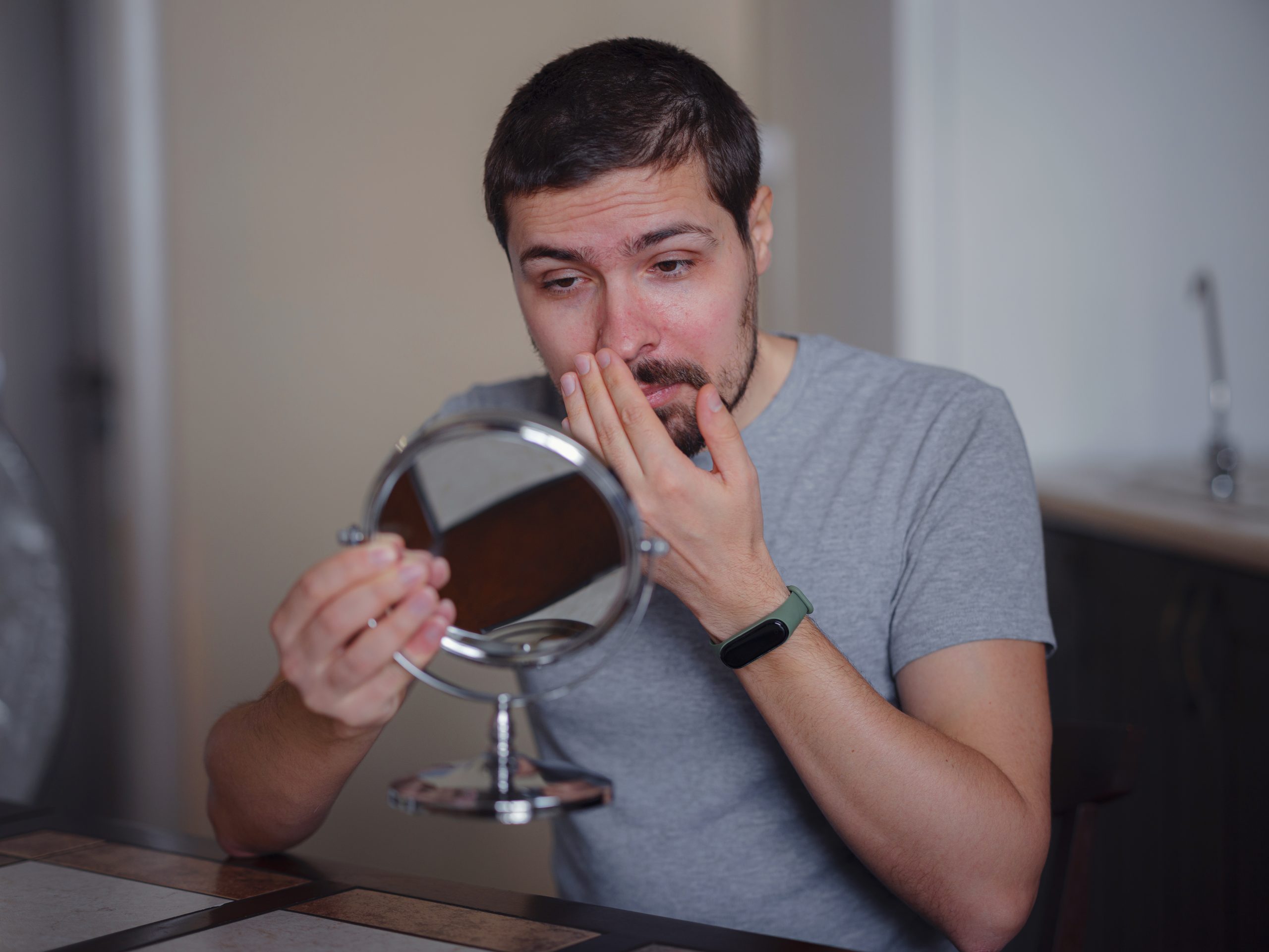 a man checking his face in a mirror due to alcoholic face swelling