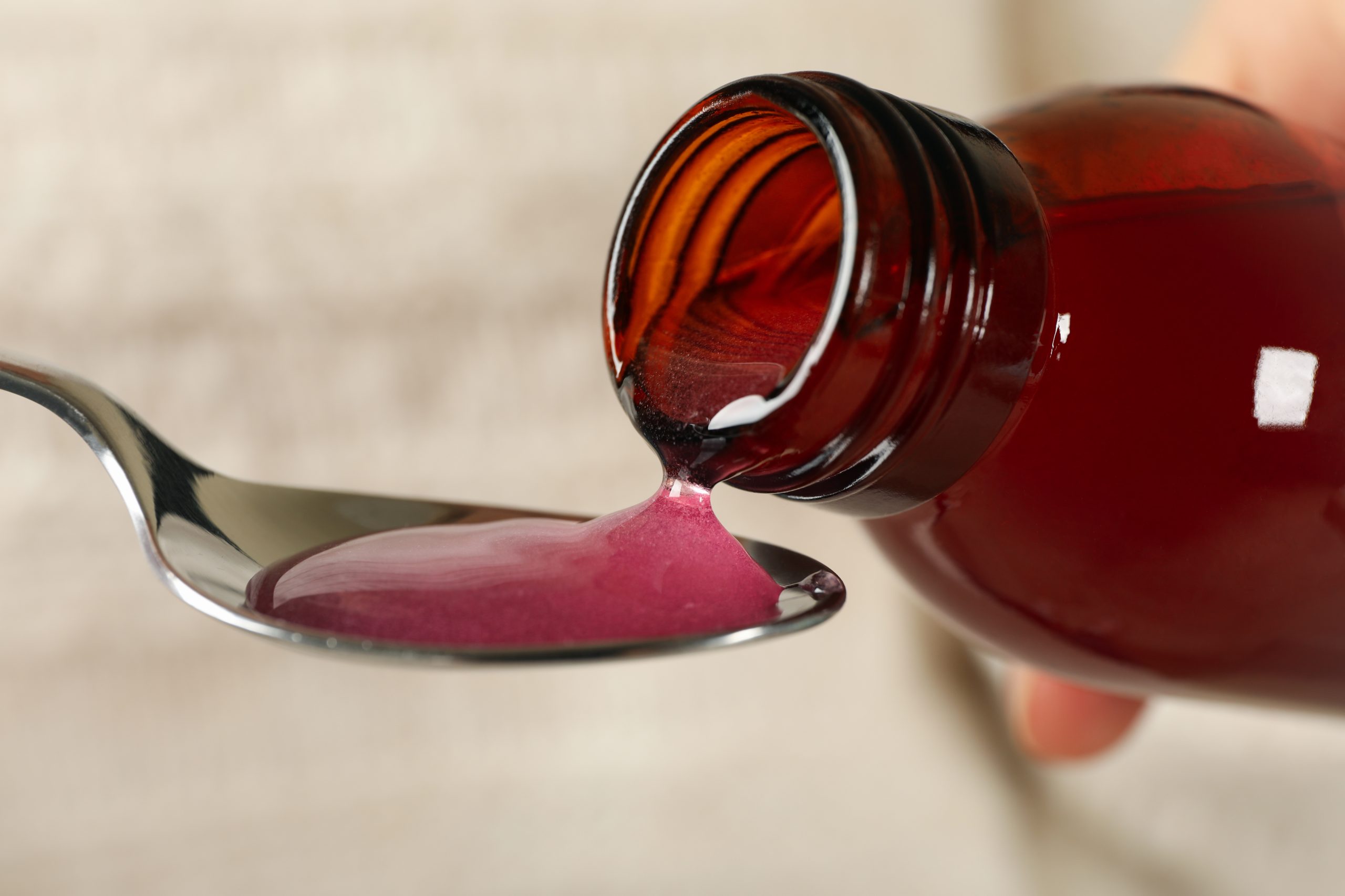 cough syrup addiction as shown by pouring cough syrup from a bottle onto a spoon