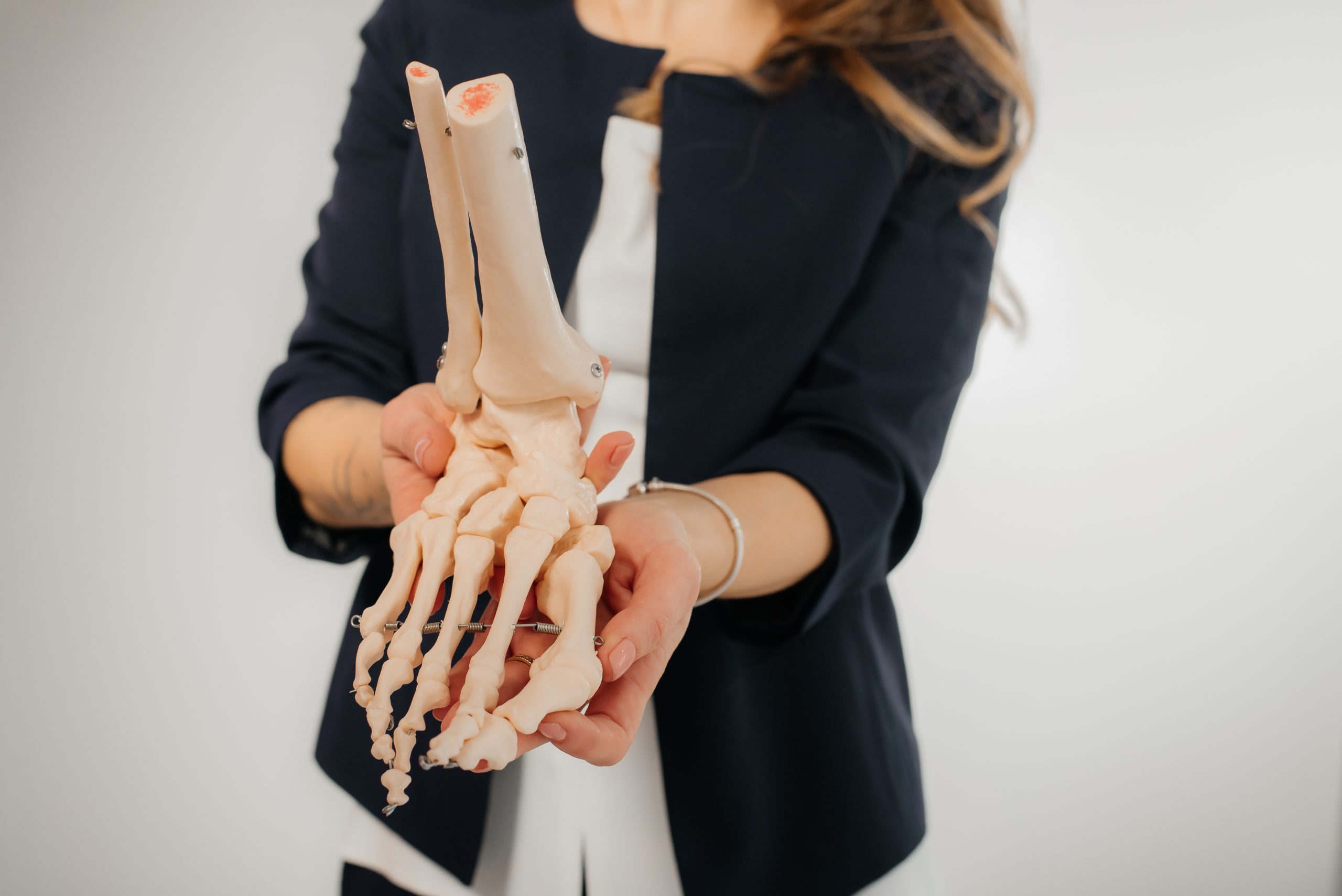 a woman holding a foot on bone model so show the link between alcohol and bone healing