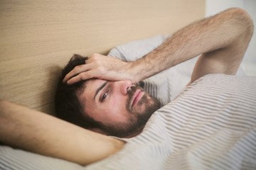 a man suffering from alcohol seizure warning signs looking at us while in bed