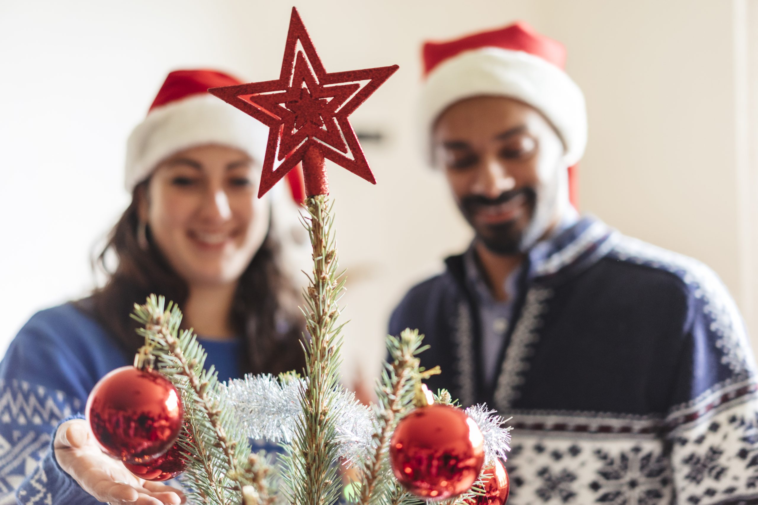 two people behind a Christmas tree having fun at a sober christmas party